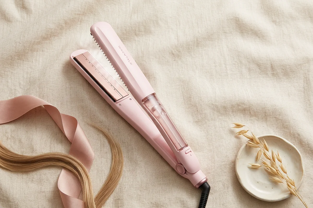 A pink nano-titanium steam hair straightener on a linen surface